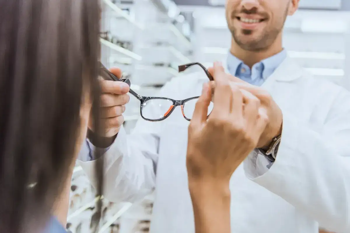 Okulista prezentuje klientce okulary, pomagając w wyborze idealnej pary. Dofinansowanie do okularów może sprawić, że nowe szkła będą na wyciągnięcie ręki.