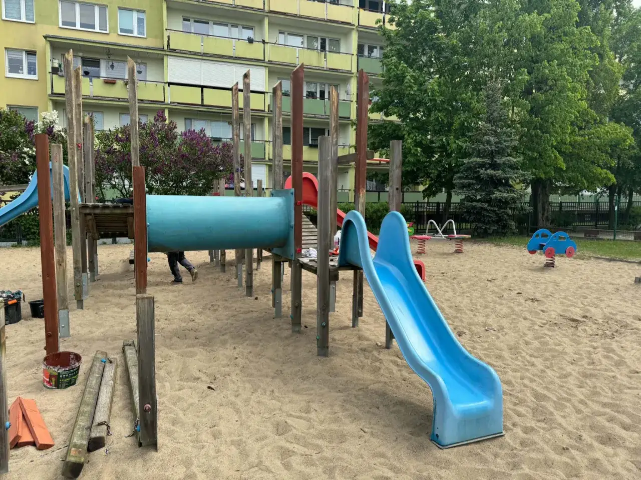 Plac zabaw przy bloku, część zespołu szkolno przedszkolnego. Piasek, zjeżdżalnie, huśtawki i drabinki.