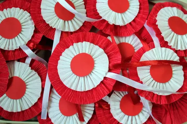Mnóstwo biało-czerwonych kotylionów z papieru marszczonego, ozdobionych wstążkami, gotowych na świętowanie.