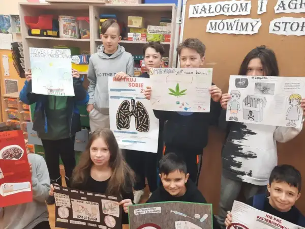 Dzieci prezentują plakaty o szkodliwości używek, pokazując jak zrobić projekt artystyczno-edukacyjny.