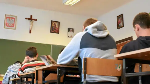Uczniowie siedzą w klasie z portretem papieża i krzyżem na ścianie. Czy religia wlicza się do średniej?