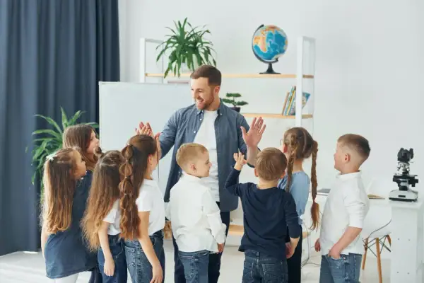 Nauczyciel z uśmiechem daje piątki dzieciom, jakby właśnie skończył się rok szkolny i nadszedł czas, kiedy jest wystawienie ocen.