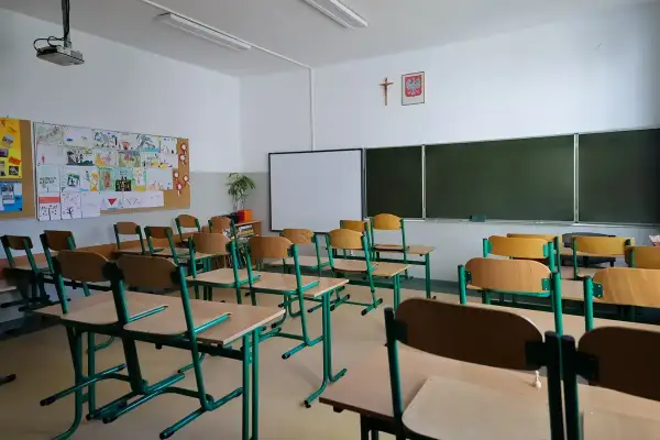 Pusta klasa z rzędami ławek i krzeseł, tablicą i projektorem. Może to być dzień przed **dniami dyrektorskimi**, kiedy wszystko jest przygotowane.
