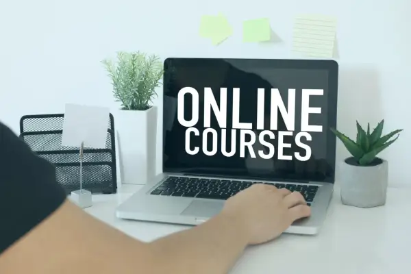 Osoba korzysta z laptopa z napisem "ONLINE COURSES". To idealne miejsce do rozpoczęcia kursu rejestratorka medyczna online.