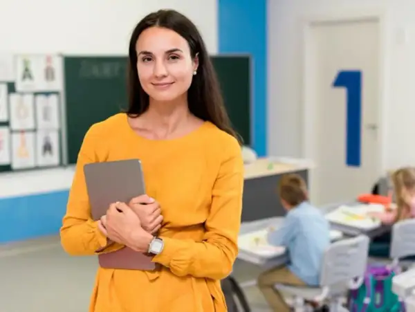 Nauczycielka z tabletem w klasie, przygotowująca się do zajęć, które mogą być częścią studiów podyplomowych nauczyciel wspomagający.