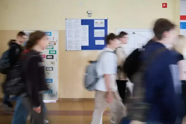 Uczniowie spieszą się korytarzem szkolnym, gdzie wiszą ogłoszenia. Może to być ważna informacja od minister edukacji narodowej.